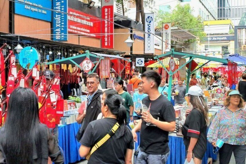 A bustling outdoor market with various stalls and people shopping. 2