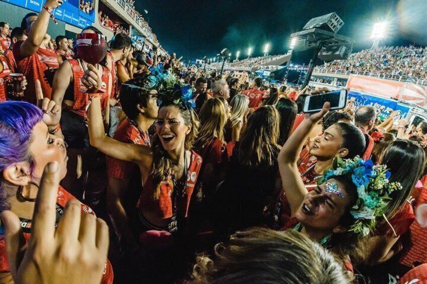 A crowded event with people in red attire, some wearing flower crowns. 1
