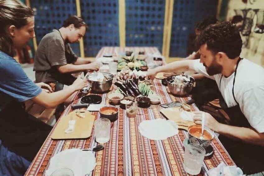 A group of people around a table with food and drinks, suggesting a communal meal or gathering. 3