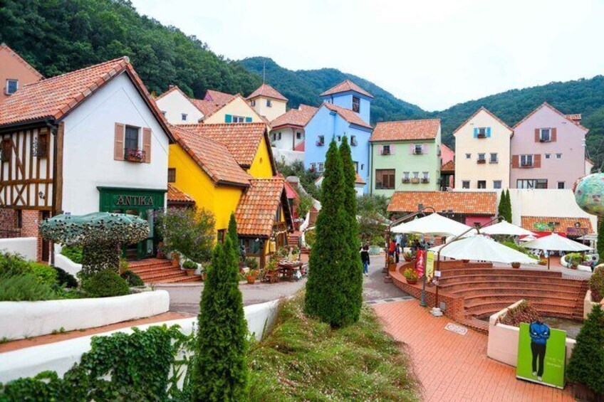 A colorful village with traditional architecture, a central square, and a mountain backdrop. 3