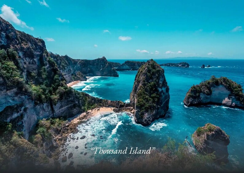 A coastal landscape with rocky outcrops, clear turquoise waters, and a sandy beach. 2