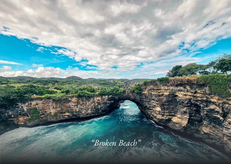 A natural arch formation over a body of water, surrounded by greenery and hills. 5