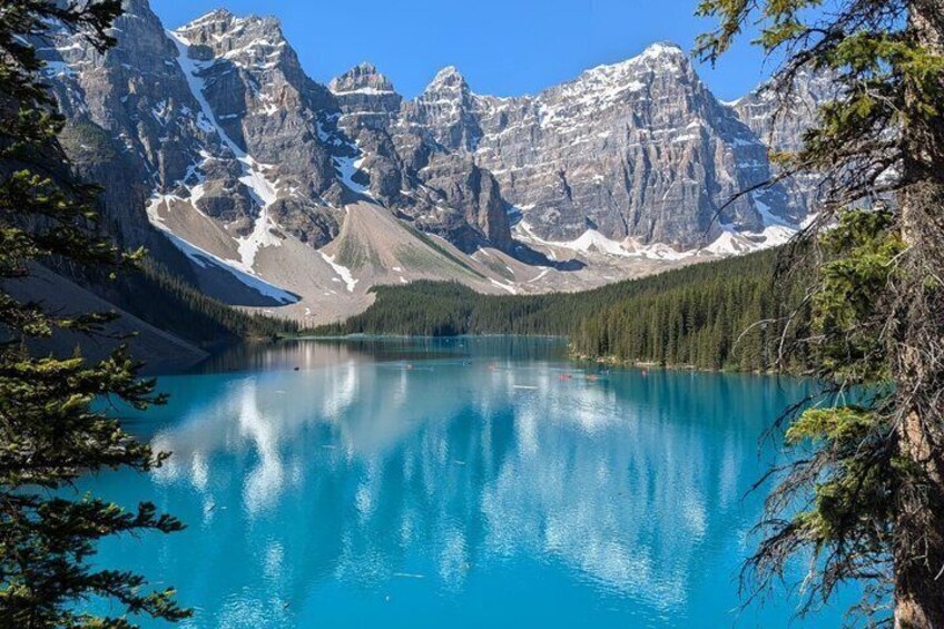 A turquoise lake surrounded by mountains with snow-capped peaks and dense forest. 3