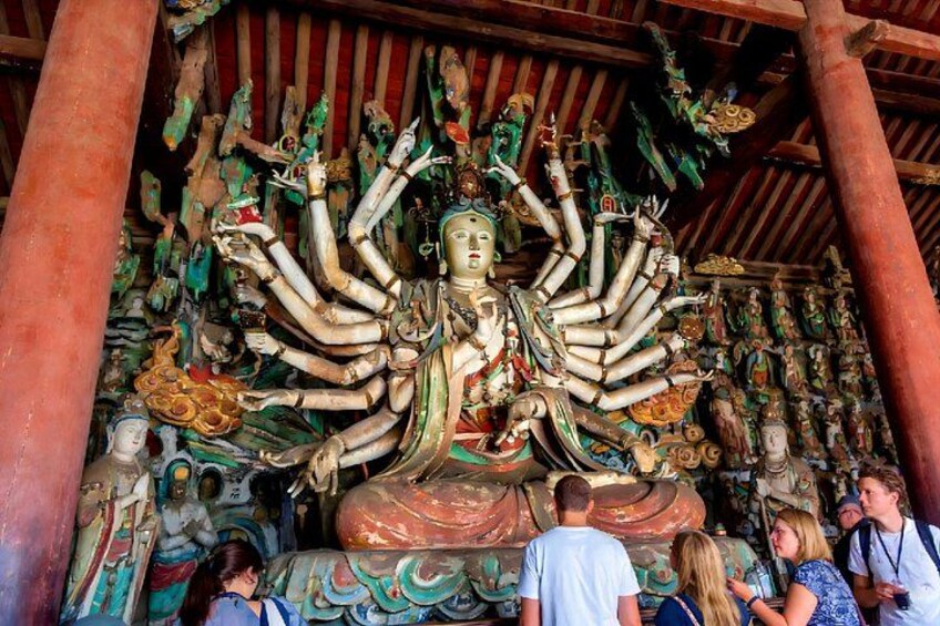 A multi-armed deity statue surrounded by various colorful figures and decorations. 1