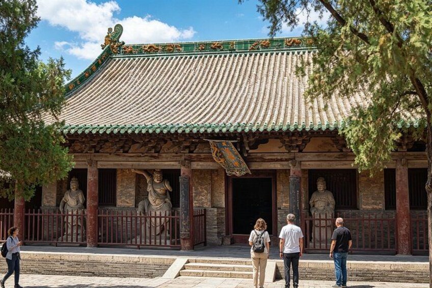 A traditional Chinese building with a tiled roof, stone statues, and a large gate. 5