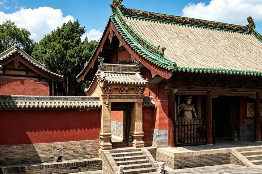 A traditional Chinese building with a tiled roof, a statue, and a stone staircase. 2