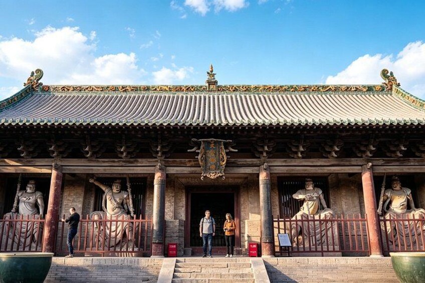 A traditional Chinese building with ornate roof tiles, statues, and a large green pot in the foreground. 4