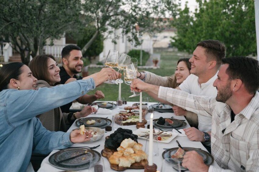 A group of people toasting at a table with various dishes and drinks. 2