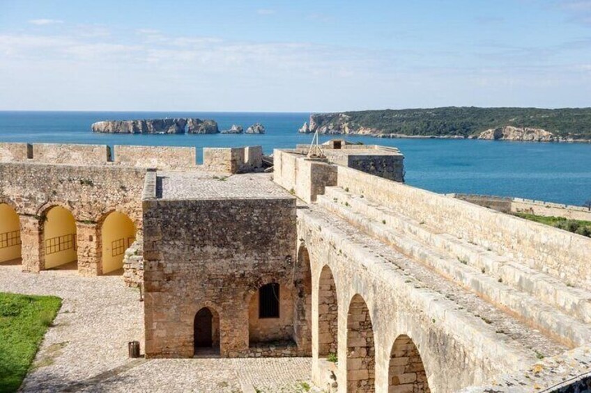 A historic stone fortress with arched walkways and a view of the sea. 5