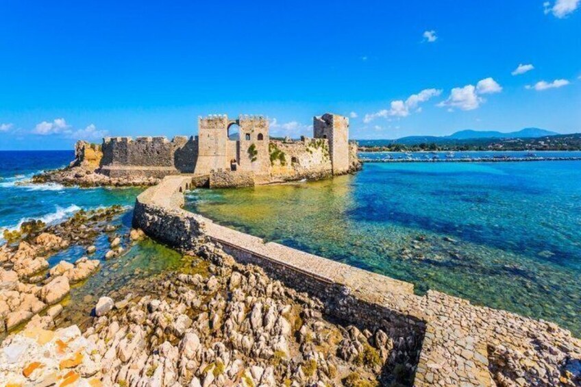 A coastal castle with clear blue waters and rocky shore. 4