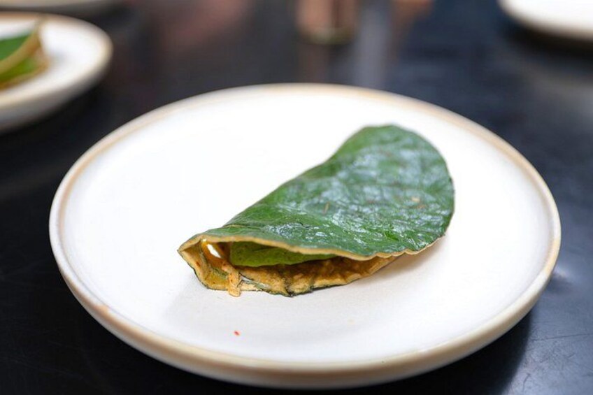 A single green crepe on a white plate. 3