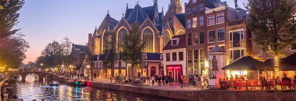 A canal with boats, a bridge, and historic buildings with illuminated windows. 1