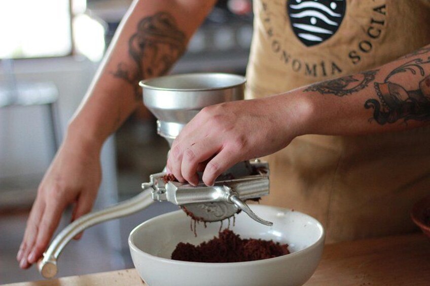 A person using a manual grinder to process food in a kitchen. 2