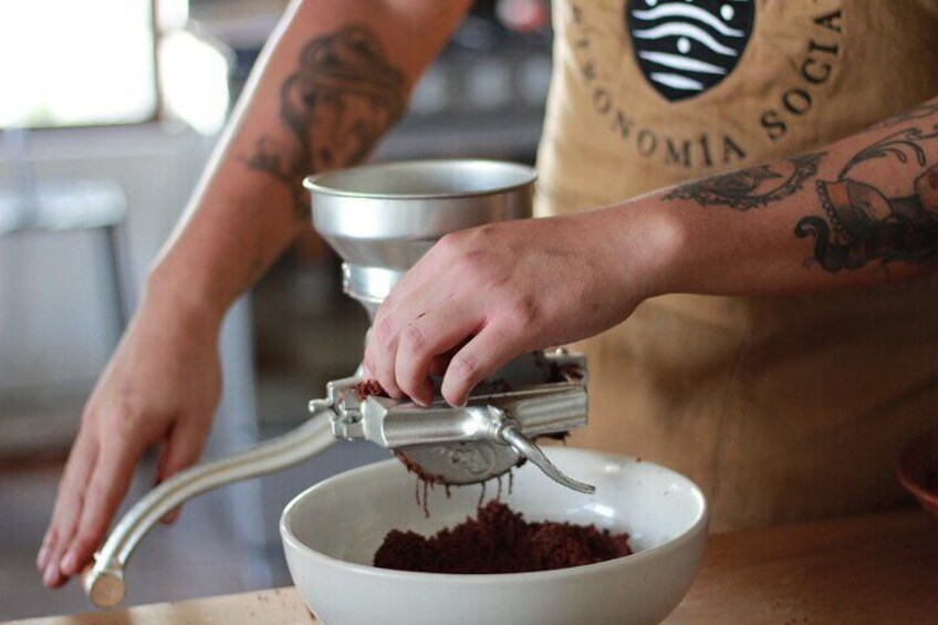 A person using a manual food processor to grind ingredients into a bowl. 2