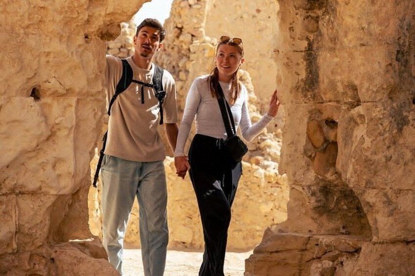 Two people walking through a rocky cave with a narrow passage. 3