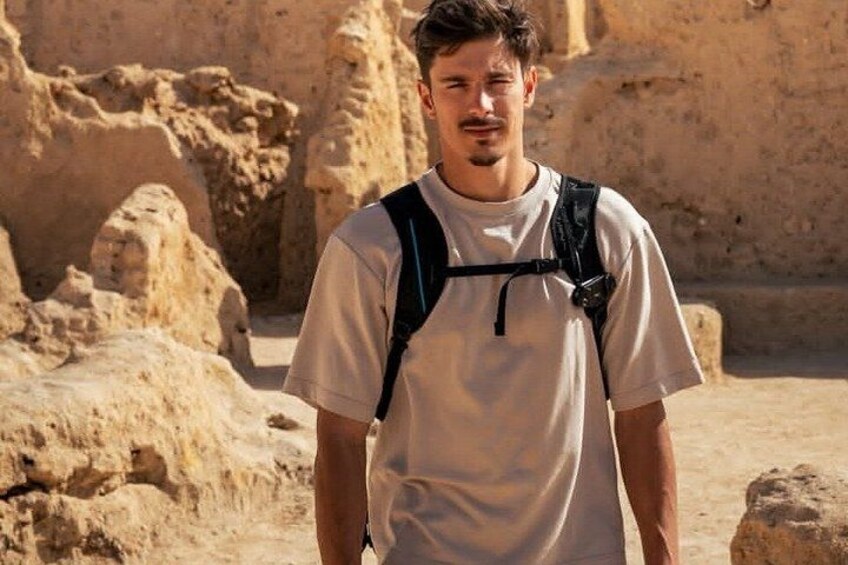 A person standing in an archaeological site with ancient ruins in the background. 2