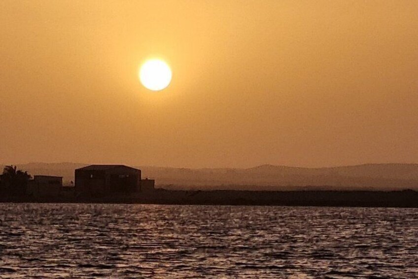 A sunset over a body of water with a distant building silhouette. 5
