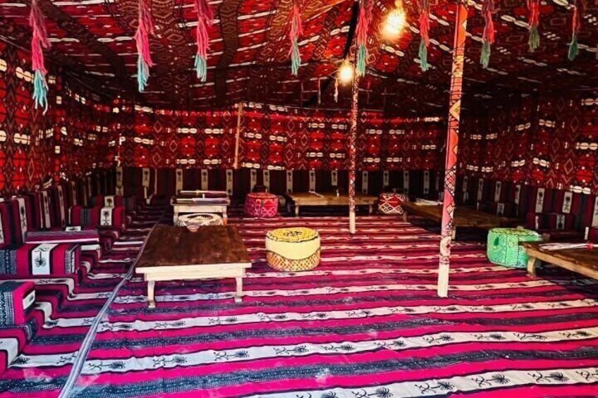 A room with patterned carpets, a wooden bench, and hanging lights. 2