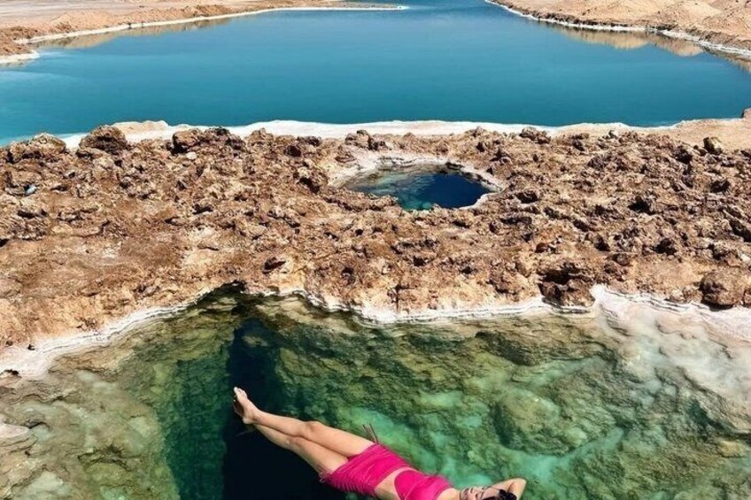 A person swimming in a clear pool with rocky edges. 4