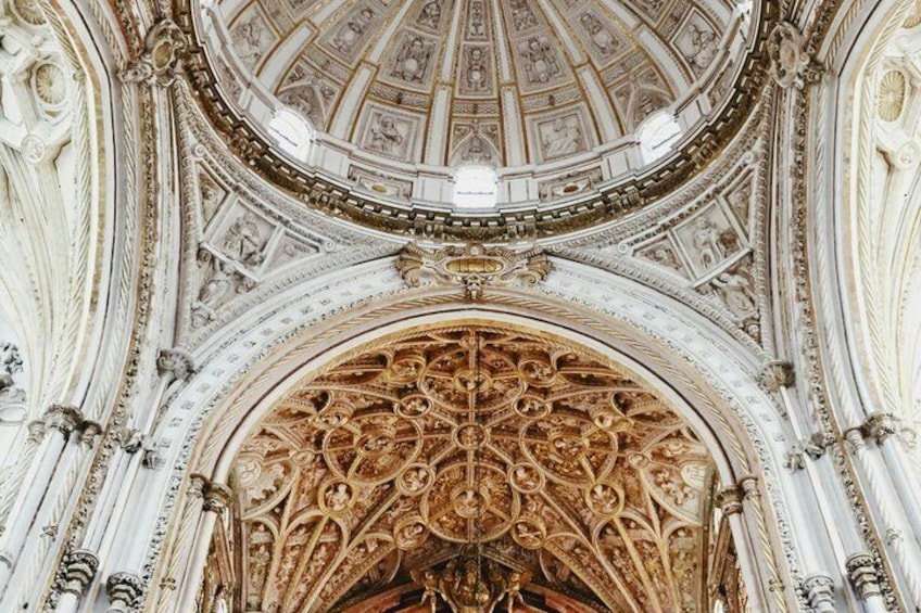 An ornate architectural ceiling with intricate carvings and a central golden design. 1