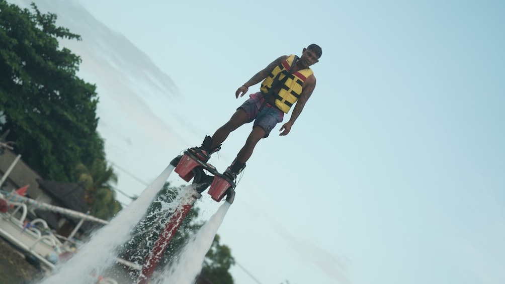 A person performing a water stunt on a jetpack. 4