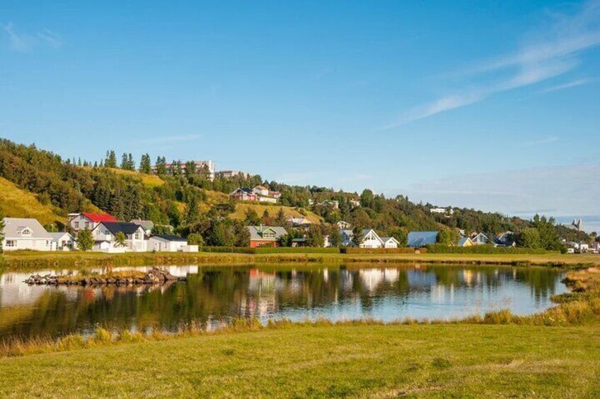 A lakeside village with houses, a hilltop, and a clear sky. 4
