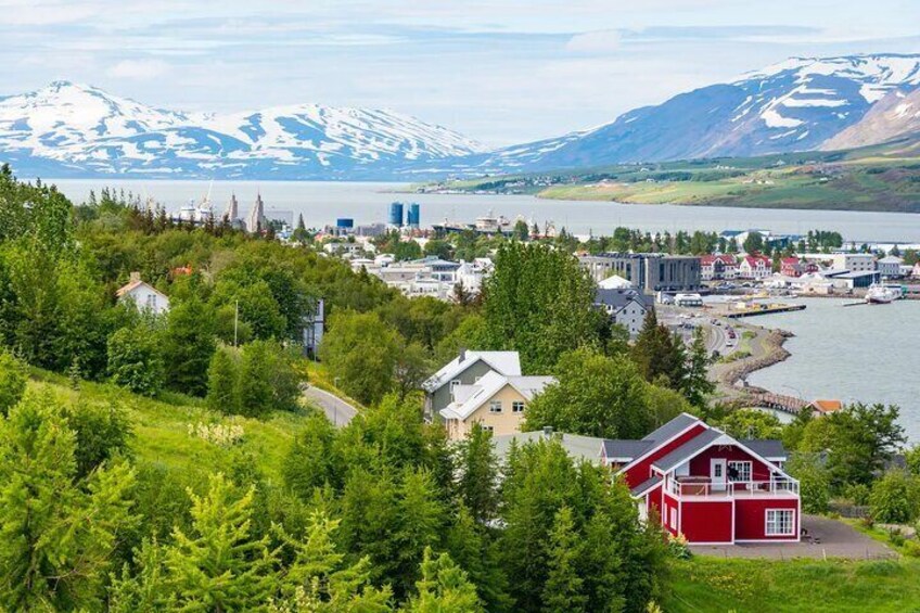 A coastal town with houses, a red building, and a mountain range in the background. 3