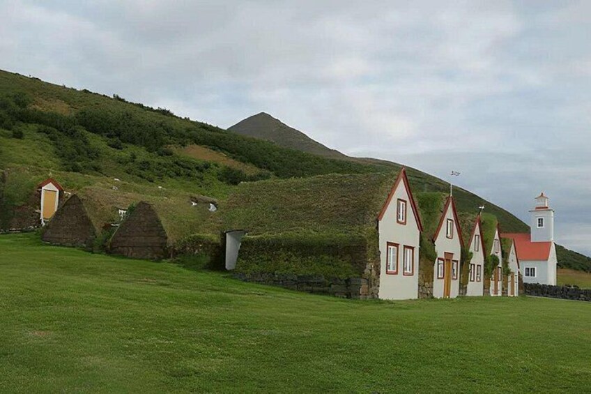 A rural landscape with traditional houses, a church, and a hill. 3