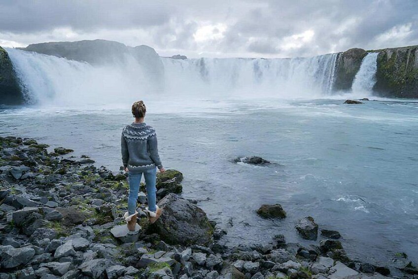 A person standing on rocks by a waterfall. 1