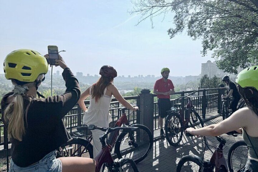 People on bicycles, a cityscape in the background, and a bridge. 1