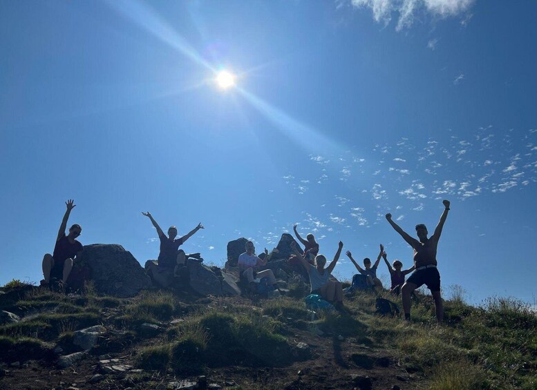 A group of people celebrating on a grassy hill with the sun shining in the background. 3