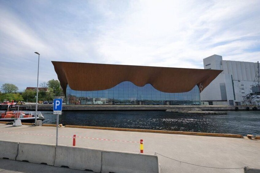 A modern building with a unique roof structure near a body of water. 3
