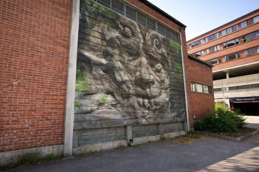 A mural on a brick wall, a parking garage, and a clear sky. 4