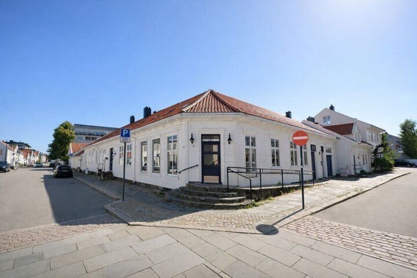 A white building with a red roof, a no entry sign, and a parking sign on the street. 1