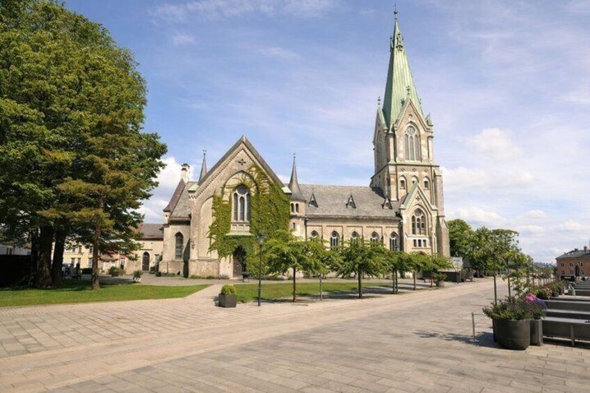 A church with a tall spire and a courtyard with trees. 5