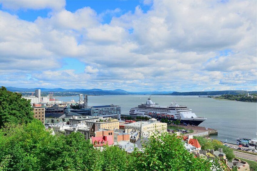 Un crucero amarrado en un puerto con edificios y vegetación al frente. 5