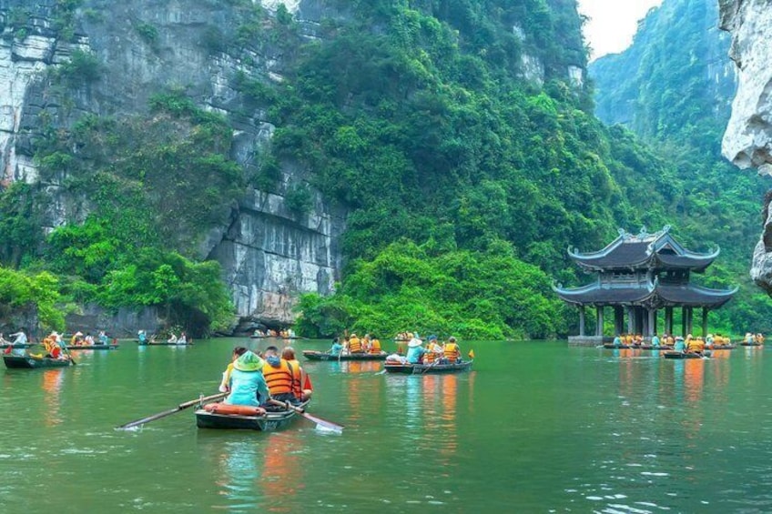 A river with boats, a traditional pavilion, and lush greenery. 2