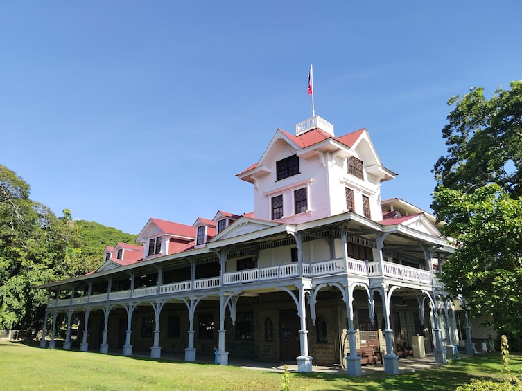 A large, white colonial-style building with a red roof and a flag on top. 2