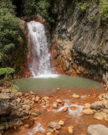 A waterfall cascading into a pool surrounded by rocks and greenery. 1