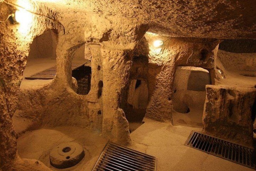 A cave interior with stalactites, a water feature, and a light source. 1