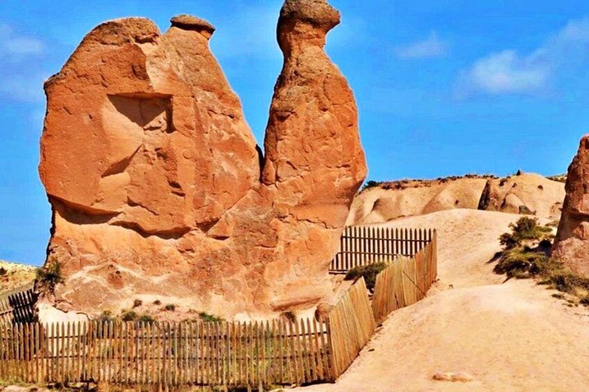 A desert landscape with prominent rock formations and a wooden fence. 3