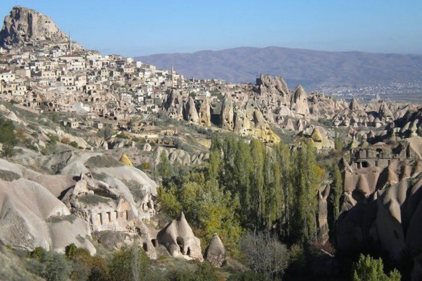 Un pueblo ubicado entre formaciones rocosas singulares, con una montaña imponente al fondo. 2