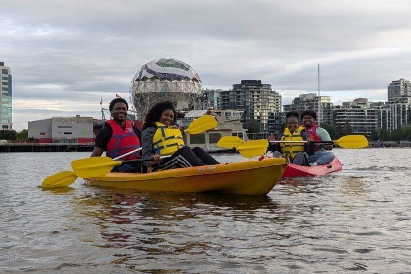 People kayaking on a river with a cityscape in the background. 3