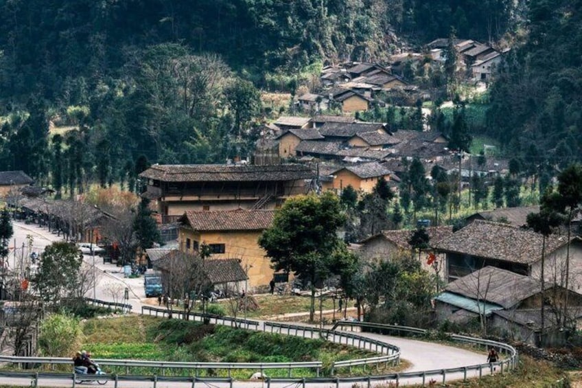 A village with traditional houses, a curved pathway, and a person cycling. 5