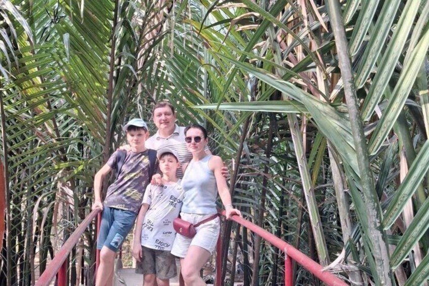 A group of people standing on a walkway surrounded by tall palm trees. 4