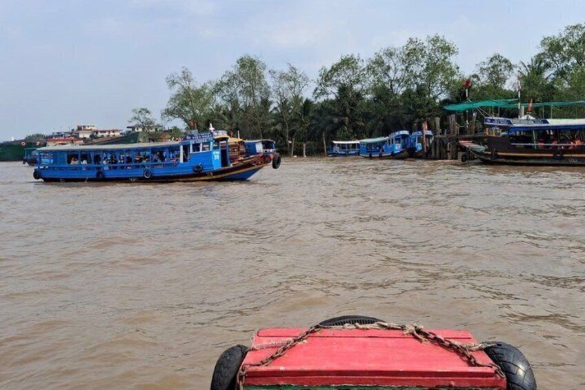 A river with boats, including a blue boat in the foreground and a red boat in the background. 4