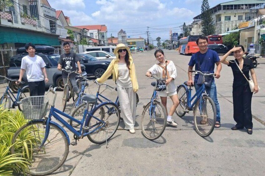 A group of people standing with bicycles in an urban street setting. 3