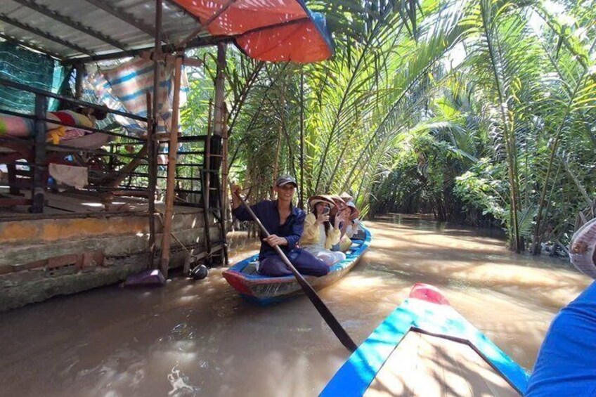 A person paddling a boat through a narrow waterway surrounded by dense tropical vegetation. 2