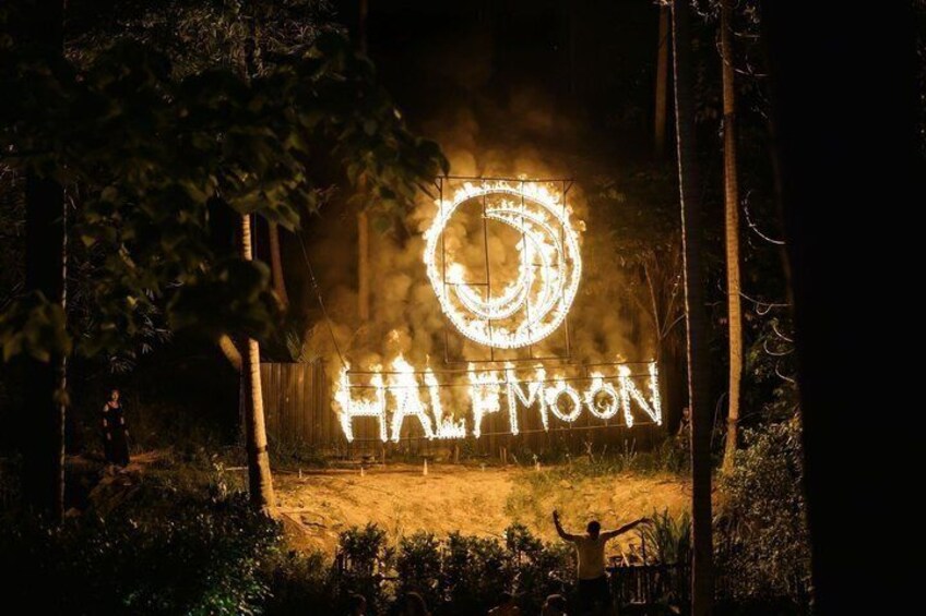 A nighttime outdoor scene with a large illuminated sign reading 'HALIFOWEN' and a circular symbol above it. 2