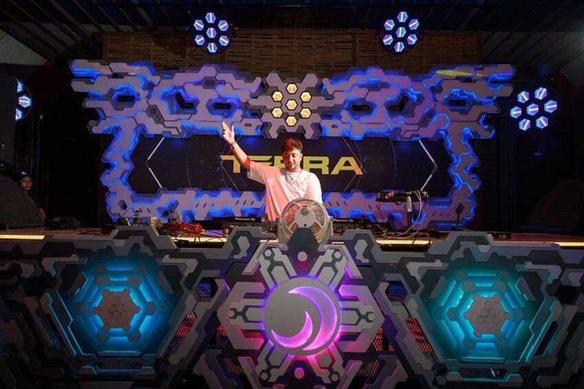 A person standing on a stage with a futuristic backdrop and a large illuminated sign. 5